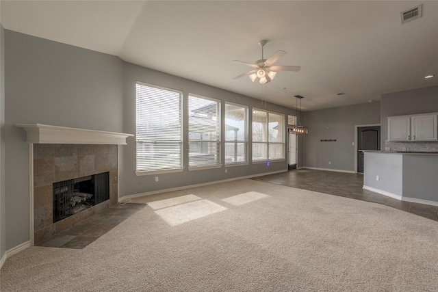 unfurnished living room featuring ceiling fan, dark colored carpet, a fireplace, and visible vents