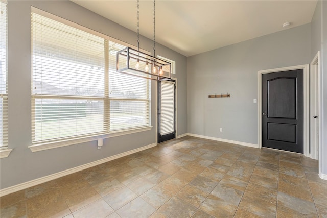 unfurnished dining area featuring stone finish flooring and baseboards