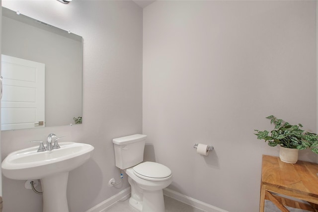 bathroom with a sink, toilet, and baseboards