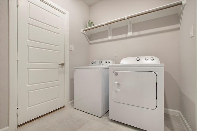 clothes washing area with baseboards, laundry area, light tile patterned flooring, and washer and dryer