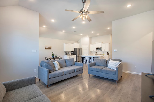 living room with lofted ceiling, ceiling fan, light wood-style flooring, recessed lighting, and baseboards