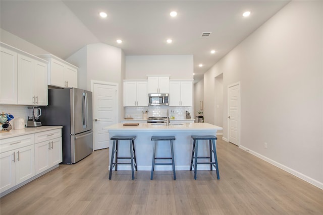 kitchen with a kitchen island with sink, white cabinetry, stainless steel appliances, and light countertops