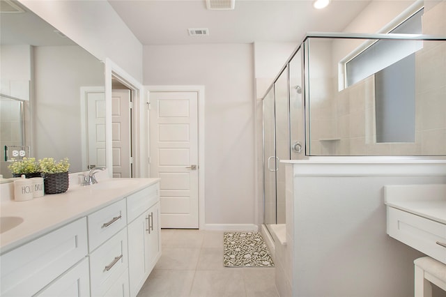 bathroom featuring double vanity, a stall shower, visible vents, tile patterned floors, and a sink