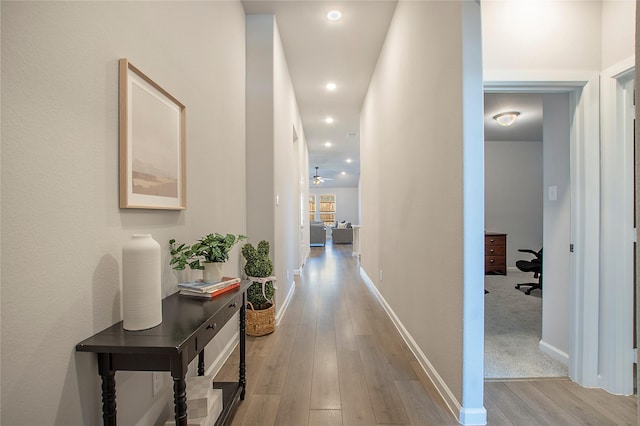 hall featuring light wood finished floors, baseboards, and recessed lighting