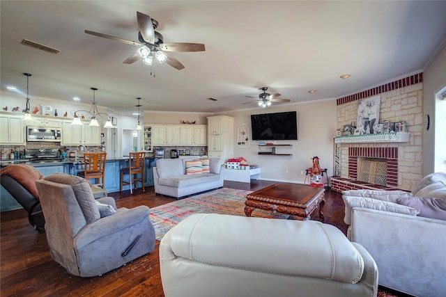 living room featuring dark wood-style floors, a brick fireplace, visible vents, and ornamental molding