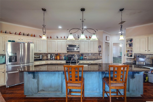 kitchen with stainless steel appliances, hanging light fixtures, a kitchen bar, and a kitchen island with sink