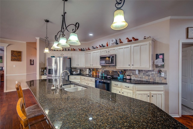 kitchen with appliances with stainless steel finishes, white cabinetry, hanging light fixtures, and a sink