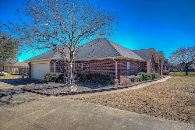 view of front facade with driveway, brick siding, roof with shingles, and an attached garage