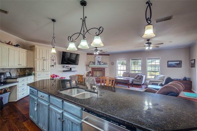 kitchen with open floor plan, a sink, hanging light fixtures, and stainless steel dishwasher