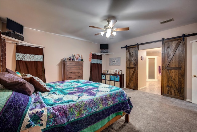 bedroom with a ceiling fan, light carpet, visible vents, and a barn door