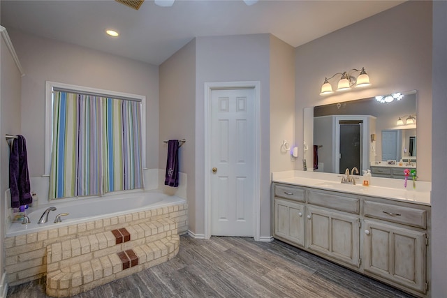 bathroom with a garden tub, wood finished floors, and vanity