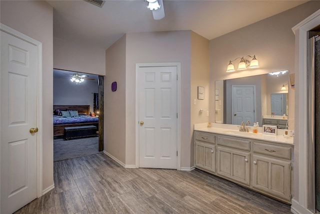 ensuite bathroom with a ceiling fan, ensuite bath, vanity, wood finish floors, and a closet