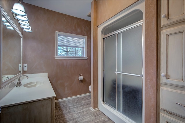 full bathroom with toilet, vanity, a shower stall, and wood finished floors