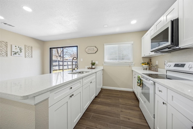 kitchen featuring white appliances, visible vents, dark wood-style flooring, a peninsula, and a sink