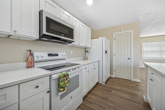 kitchen with dark wood-type flooring, white appliances, white cabinetry, and baseboards