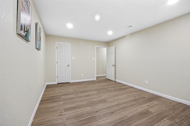 empty room featuring recessed lighting, wood finished floors, visible vents, and baseboards