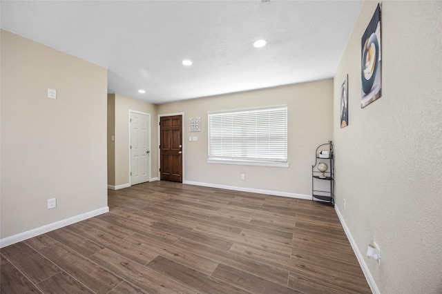 empty room with baseboards, wood finished floors, and recessed lighting