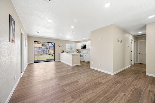 unfurnished living room with visible vents, recessed lighting, light wood-style flooring, and baseboards