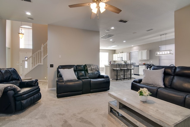 living room with stairs, baseboards, visible vents, and light colored carpet