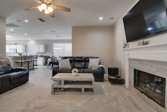 living area featuring light carpet, a tile fireplace, visible vents, and recessed lighting