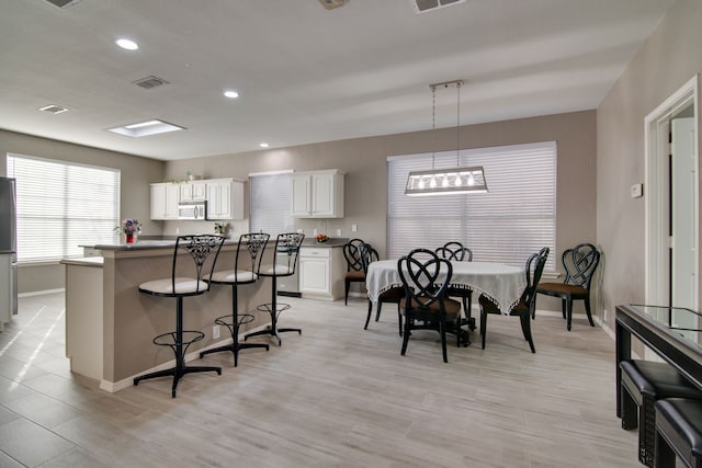 kitchen featuring visible vents, a breakfast bar area, stainless steel appliances, white cabinetry, and recessed lighting