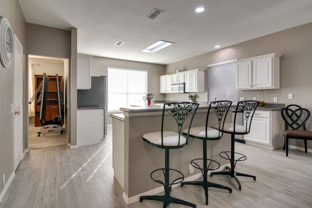 kitchen featuring dark countertops, appliances with stainless steel finishes, visible vents, and white cabinets