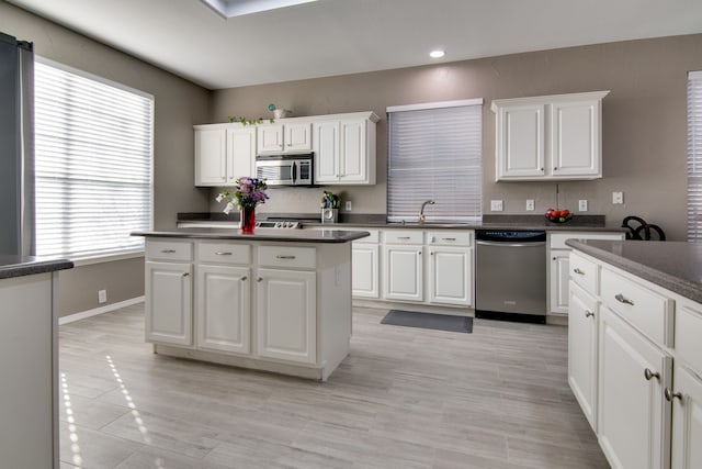 kitchen with dark countertops, white cabinetry, appliances with stainless steel finishes, and a sink