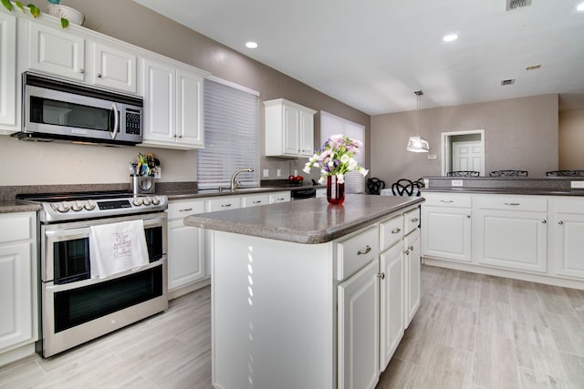 kitchen with appliances with stainless steel finishes, dark countertops, and a kitchen island