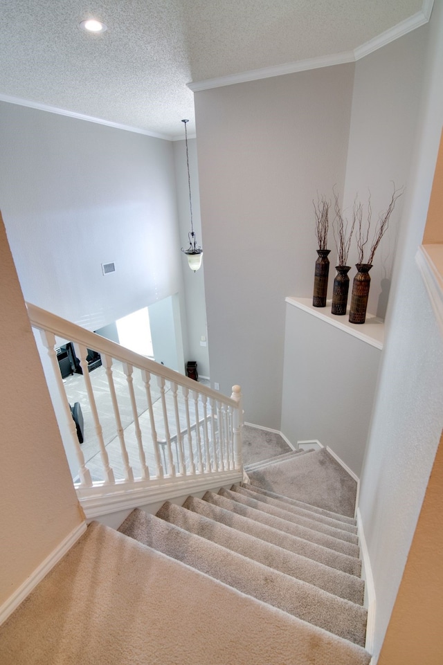 stairway with baseboards, visible vents, ornamental molding, and a textured ceiling