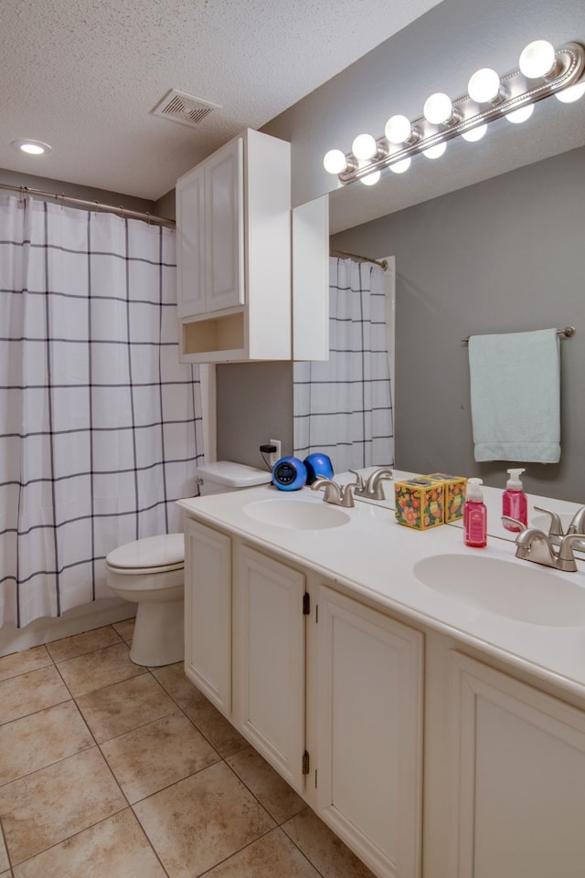 bathroom with a textured ceiling, tile patterned flooring, a sink, and toilet