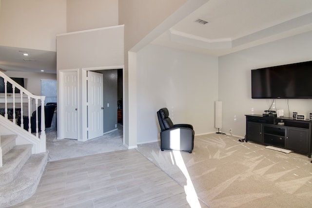 interior space featuring stairs, visible vents, a raised ceiling, and light colored carpet