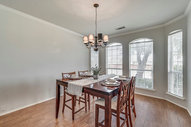 dining area with visible vents, a chandelier, wood finished floors, and ornamental molding