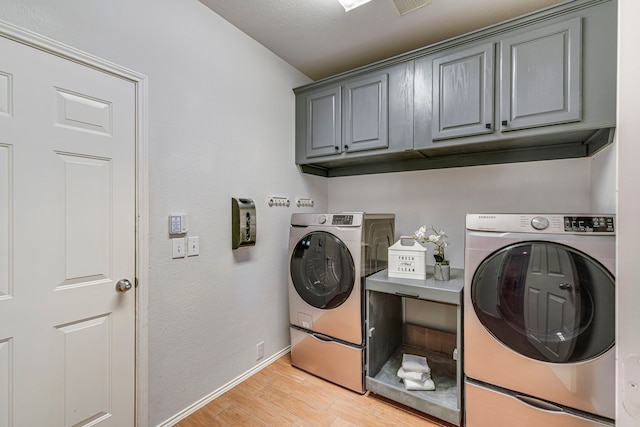 laundry room with light wood-type flooring, cabinet space, baseboards, and washer and clothes dryer