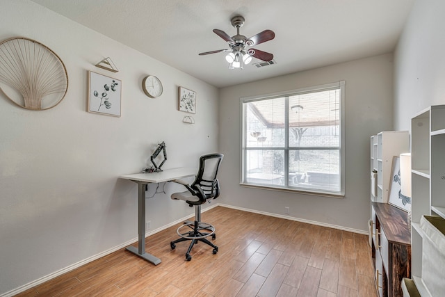 office space with ceiling fan, light wood-type flooring, visible vents, and baseboards