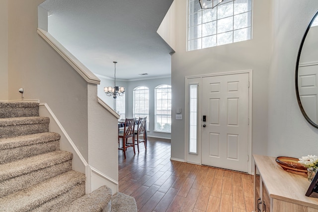 entryway featuring light wood-style flooring, stairs, ornamental molding, and a notable chandelier