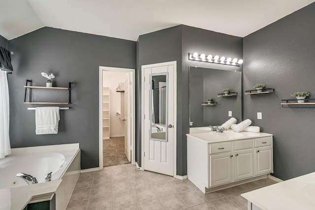 full bathroom featuring two vanities, vaulted ceiling, a sink, a jetted tub, and tile patterned floors