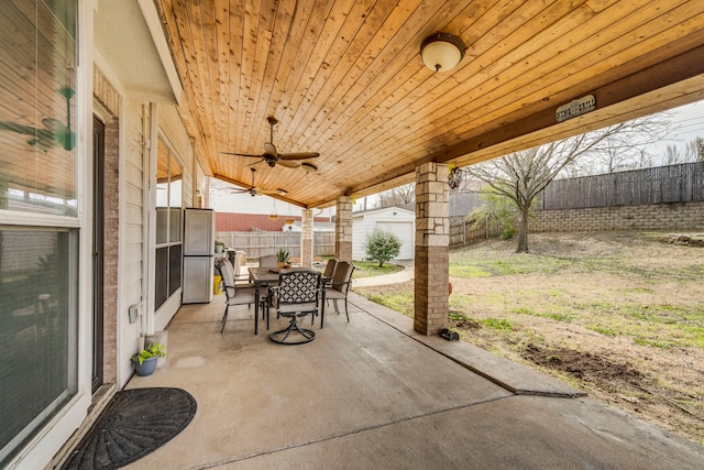 view of patio / terrace with a ceiling fan, an outbuilding, outdoor dining area, and a fenced backyard