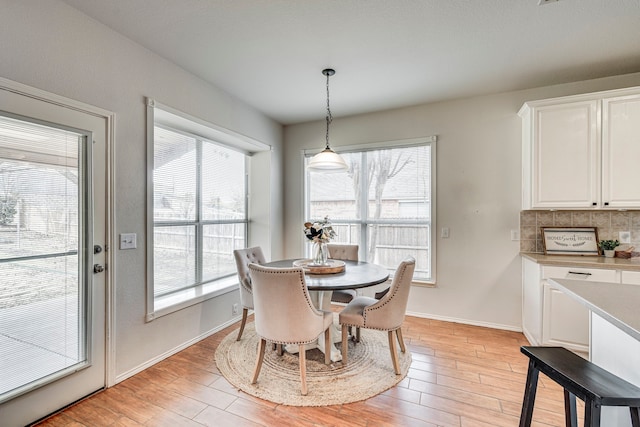 dining space featuring light wood-style flooring and baseboards