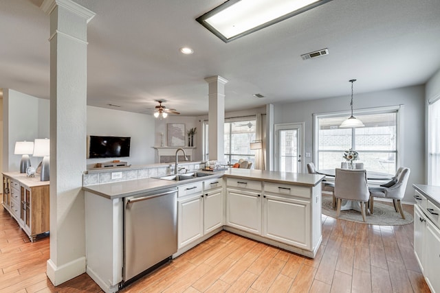 kitchen featuring light wood-style flooring, a sink, open floor plan, dishwasher, and decorative columns