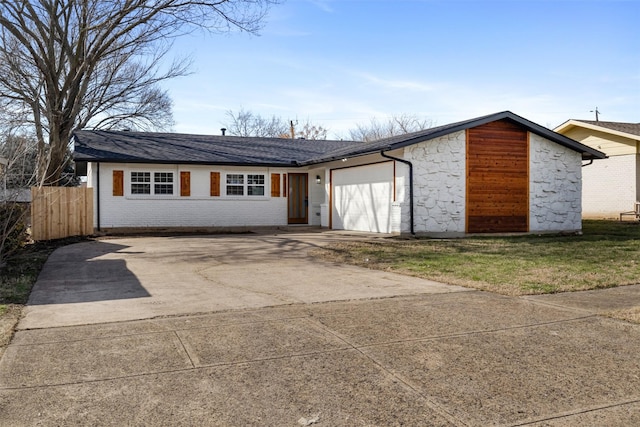 view of front facade with roof with shingles, concrete driveway, fence, a garage, and stone siding