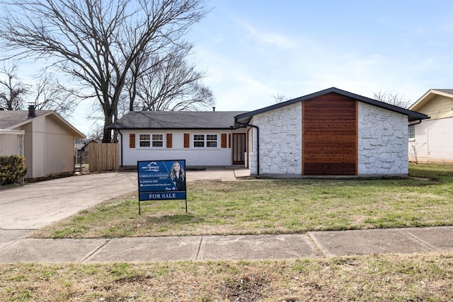 view of front of house featuring stone siding, fence, and a front yard