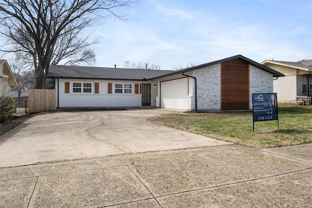 view of front of house featuring stone siding, concrete driveway, fence, and an attached garage