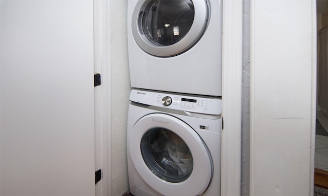 clothes washing area with stacked washing maching and dryer and laundry area