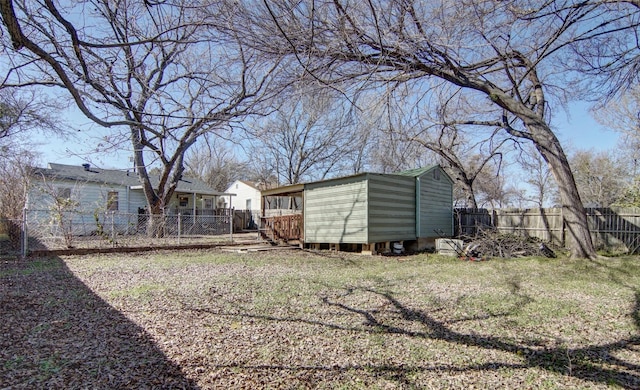 view of yard with a fenced backyard, a storage unit, and an outbuilding