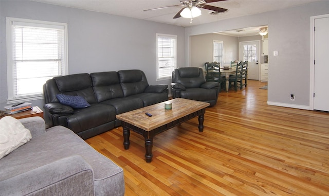 living area with light wood finished floors, plenty of natural light, baseboards, and ceiling fan