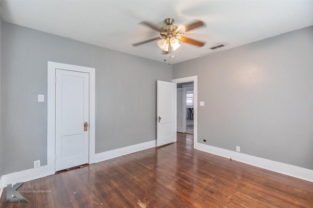 empty room with ceiling fan, dark wood-type flooring, visible vents, and baseboards