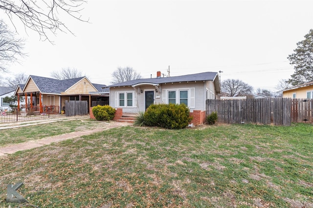 view of front of home featuring brick siding, fence, and a front lawn