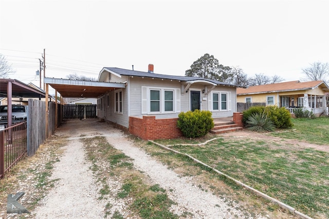 bungalow-style house with driveway, an attached carport, and fence