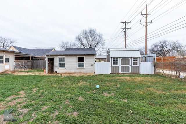 rear view of property with a storage shed, a yard, an outdoor structure, and a fenced backyard