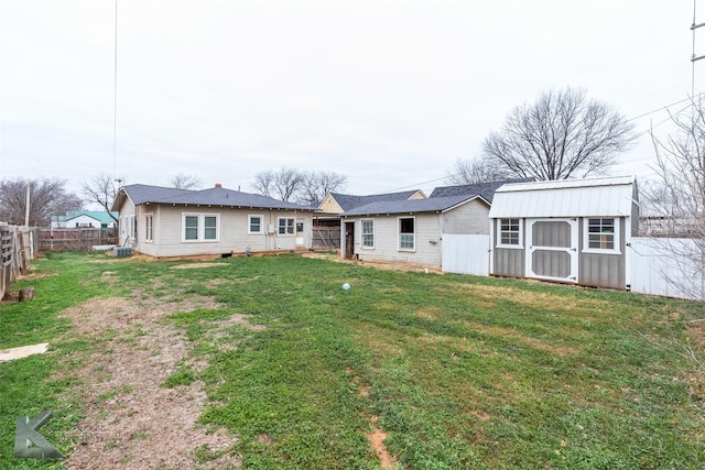 back of property featuring an outbuilding, a fenced backyard, a lawn, and a storage shed